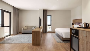 Una habitación de hotel moderna con un escritorio de madera, un sofá, una cama y una kitchenette.
