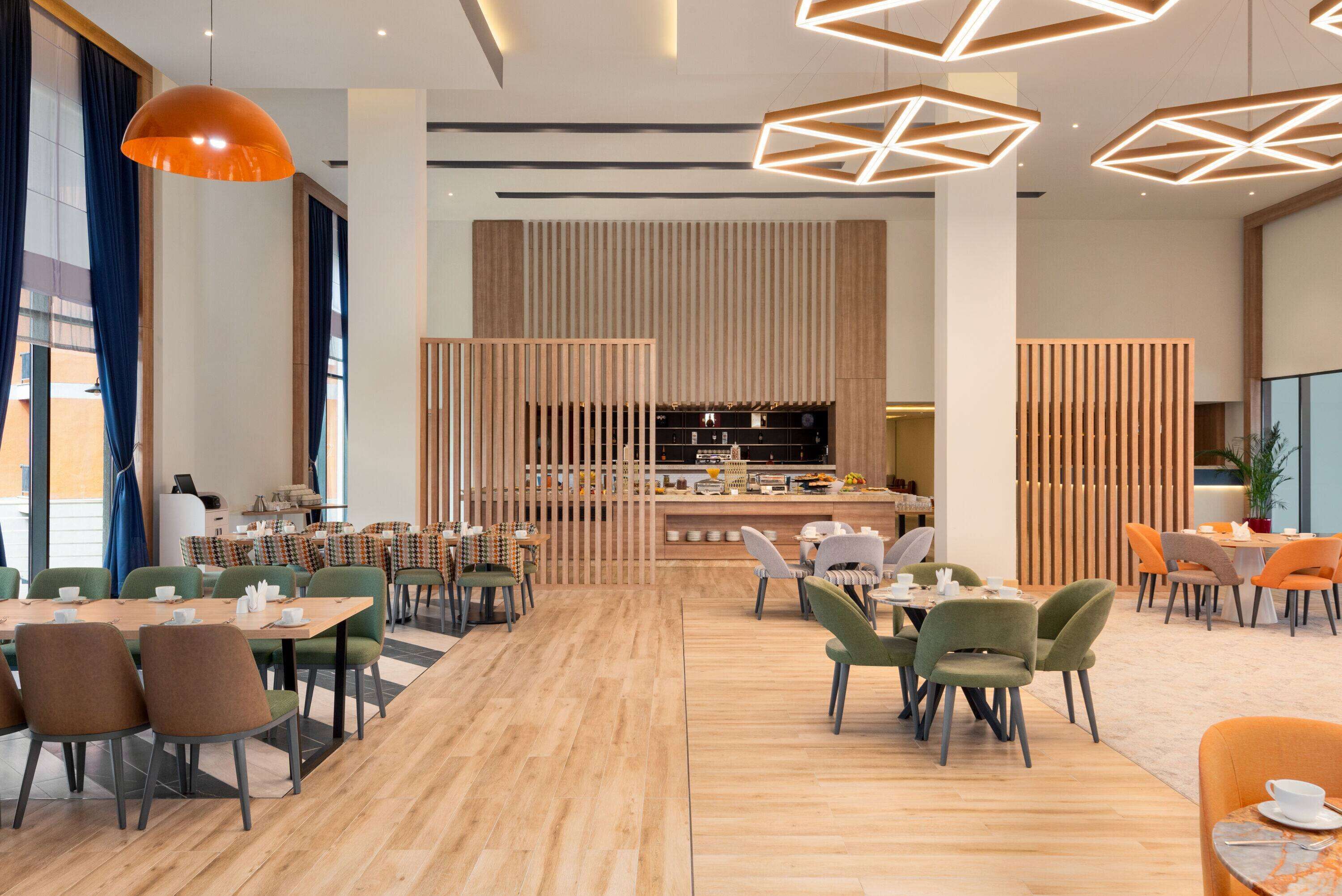 A modern dining area with wooden flooring, green and brown chairs, and a central bar area.