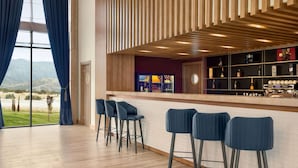 Zona de bar moderna con techo de madera, taburetes y vistas a un paisaje montañoso a través de amplias ventanas.