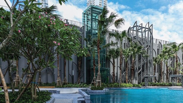 Una piscina de diseño moderno, rodeada de palmeras y un edificio con fachada de vidrio.