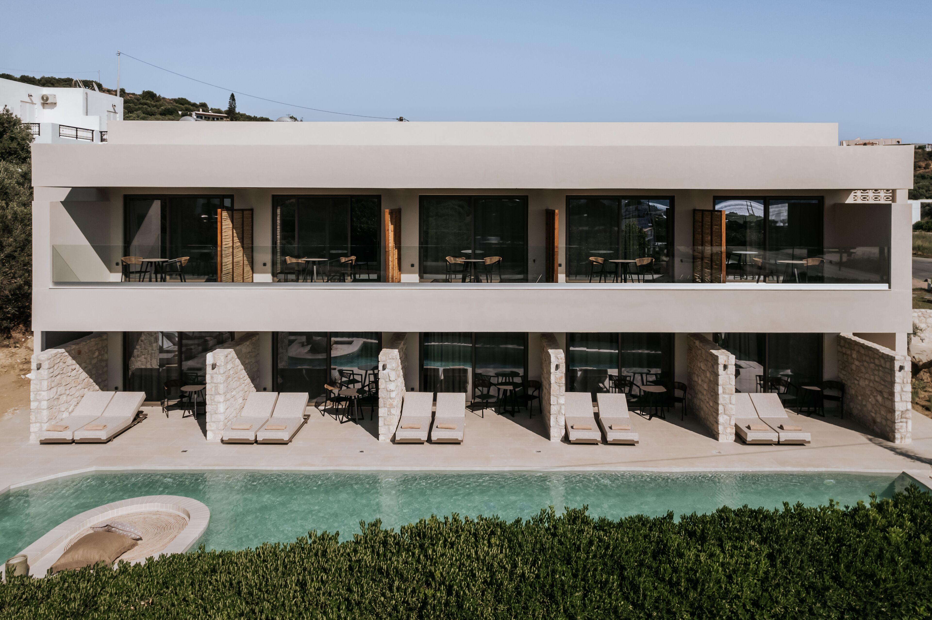 Un bâtiment moderne à deux étages, doté d’une piscine, d’un espace extérieur aménagé et offrant une vue dégagée sur le paysage environnant.