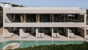 Un bâtiment moderne à deux étages, doté d’une piscine, d’un espace extérieur aménagé et offrant une vue dégagée sur le paysage environnant.