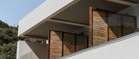 Un edificio moderno con techo plano, ventanas amplias y un balcón con listones de madera.