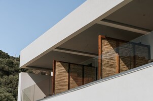 Un bâtiment moderne doté d’un toit plat, de grandes fenêtres et d’un balcon avec des lattes en bois.