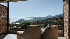 A balcony with two cushioned chairs, a view of a mountainous landscape, and a wooden slatted wall. - AMÉNTE Mindful Stay (Agios Vasileios)
