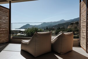 Un balcon avec deux fauteuils rembourrés, une vue sur un paysage montagneux et un mur en bois à lattes.