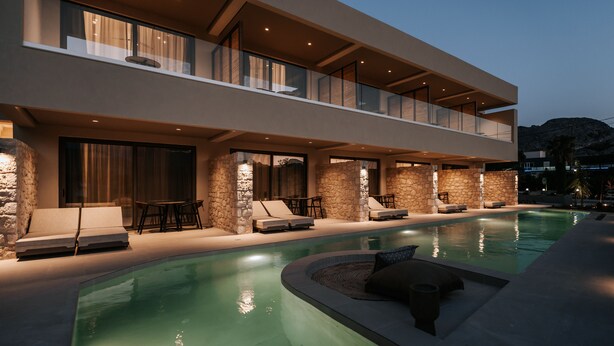 A modern two-story building with a swimming pool, outdoor seating, and stone walls. - AMÉNTE Mindful Stay (Agios Vasileios)
