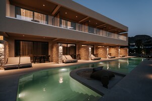 Un bâtiment moderne à deux étages doté d’une piscine, d’un espace extérieur aménagé et de murs en pierre.