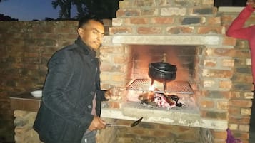 Una persona cocinando al aire libre usando un horno de ladrillo con una olla encima.