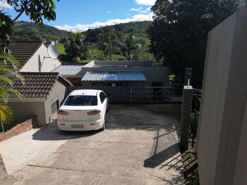 A white car parked in a driveway with a house in the background.
