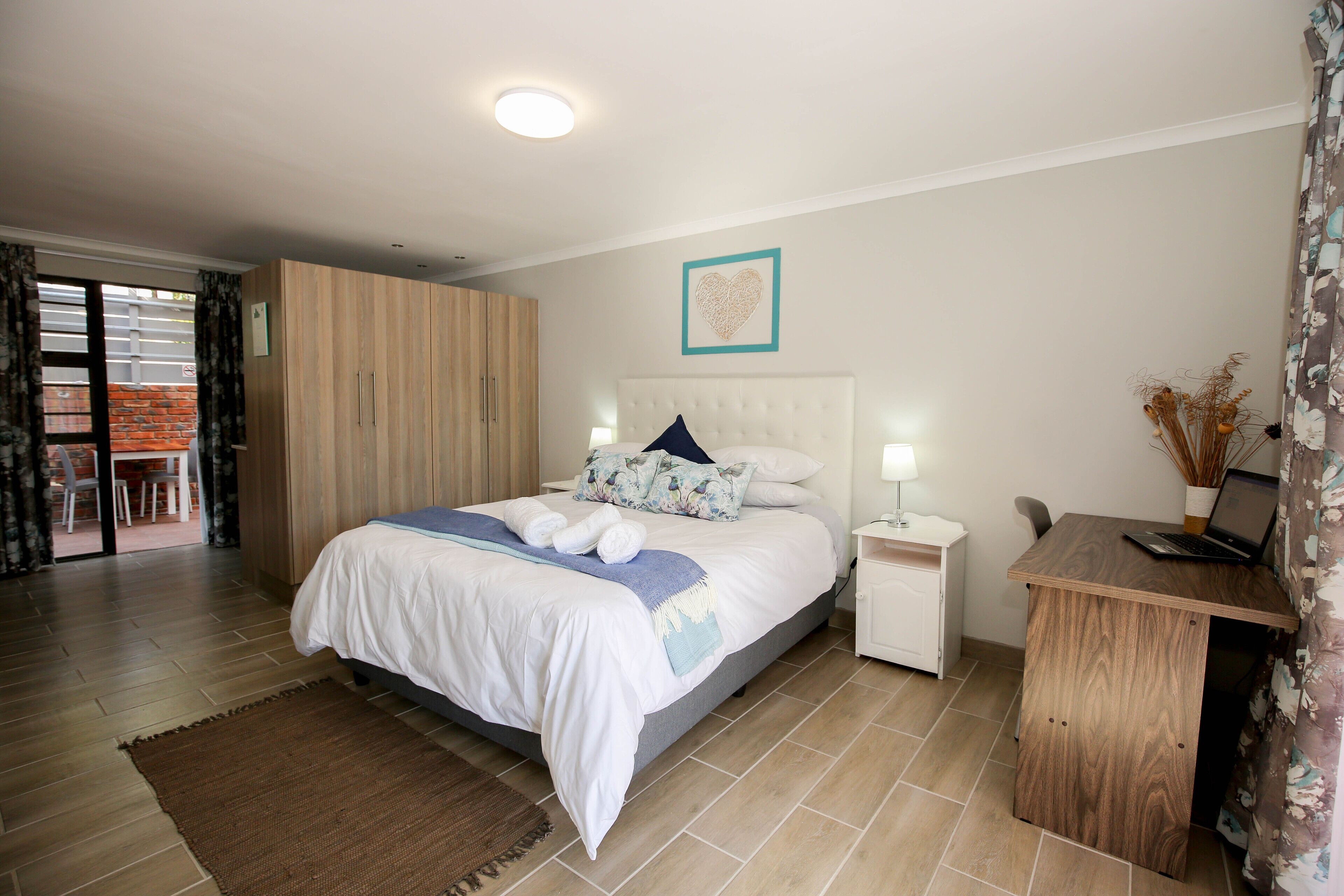 A bedroom with a bed, bedside tables, a desk, and a wardrobe.