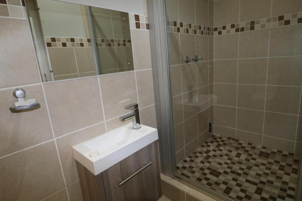 Ein Badezimmer mit Dusche, Waschbecken und Spiegel.