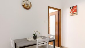 A dining area with a table, chairs, a clock, and a door. - Primula Apartment by Wonderful Italy (Bologna)