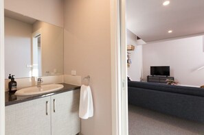 Enjoy a clean and uncluttered space with a large sink, mirror, and flat-screen TV.