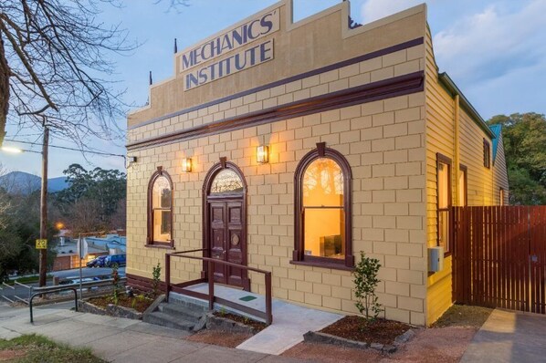 Stunning Mechanics' Institute building with a brick facade and arched windows, featuring a prominent sign and a charming garden entrance.