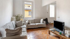 A living room with a sofa, a television, and a radiator. - Country Style House in Bologna by Wonderful Italy (Bologna)