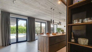 A modern kitchen with a wooden island, large windows, and a built-in bookshelf. - Villa Marli Zadarvillas (Nin)