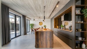 A modern kitchen with a wooden island, large windows, and a built-in bookshelf. - Villa Marli Zadarvillas (Nin)