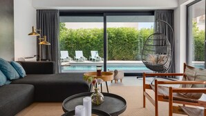 A modern living room with a large window, a pool view, a hanging chair, and a sofa. - Villa Marli Zadarvillas (Nin)
