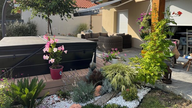Un espace patio aménagé avec du mobilier d’extérieur, un jacuzzi et diverses plantes en pot.