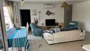 Un salon moderne avec un canapé, une table à manger et un téléviseur.