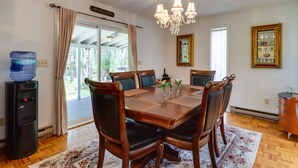 A dining room with a wooden table, leather chairs, a chandelier, and a water dispenser. - Fire Pit, Kayaks & Hammocks: Long Pond Home! (Long Pond)