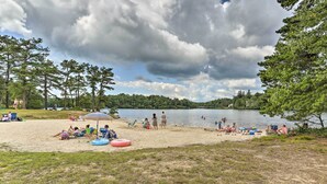 A lakeside beach with people relaxing and swimming. - Fire Pit, Kayaks & Hammocks: Long Pond Home! (Long Pond)