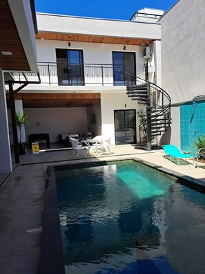 A modern building with a pool, outdoor seating, and a spiral staircase. - Hospedaria da Barra Balneário Camboriú  (Balneário Camboriú)
