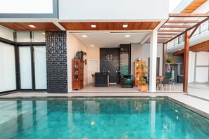 A modern indoor pool area with a clear view of the pool, a reception desk, and a seating area with a view of the pool. - Hospedaria da Barra Balneário Camboriú  (Balneário Camboriú)