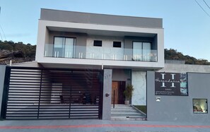 A modern two-story building with a large garage door, a balcony, and a sign advertising a hotel. - Hospedaria da Barra Balneário Camboriú  (Balneário Camboriú)