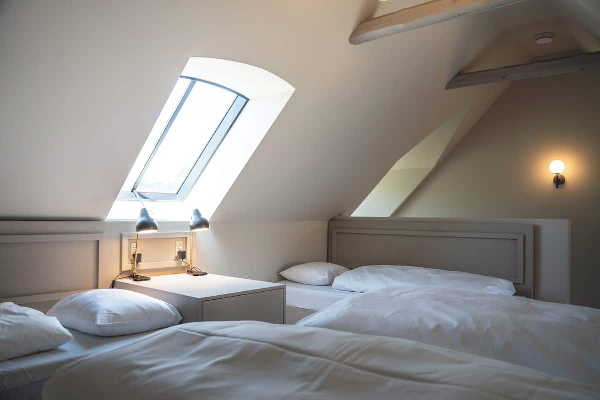 Une chambre Ă coucher avec un puits de lumiĂšre, deux tables de chevet et une tĂȘte de lit.