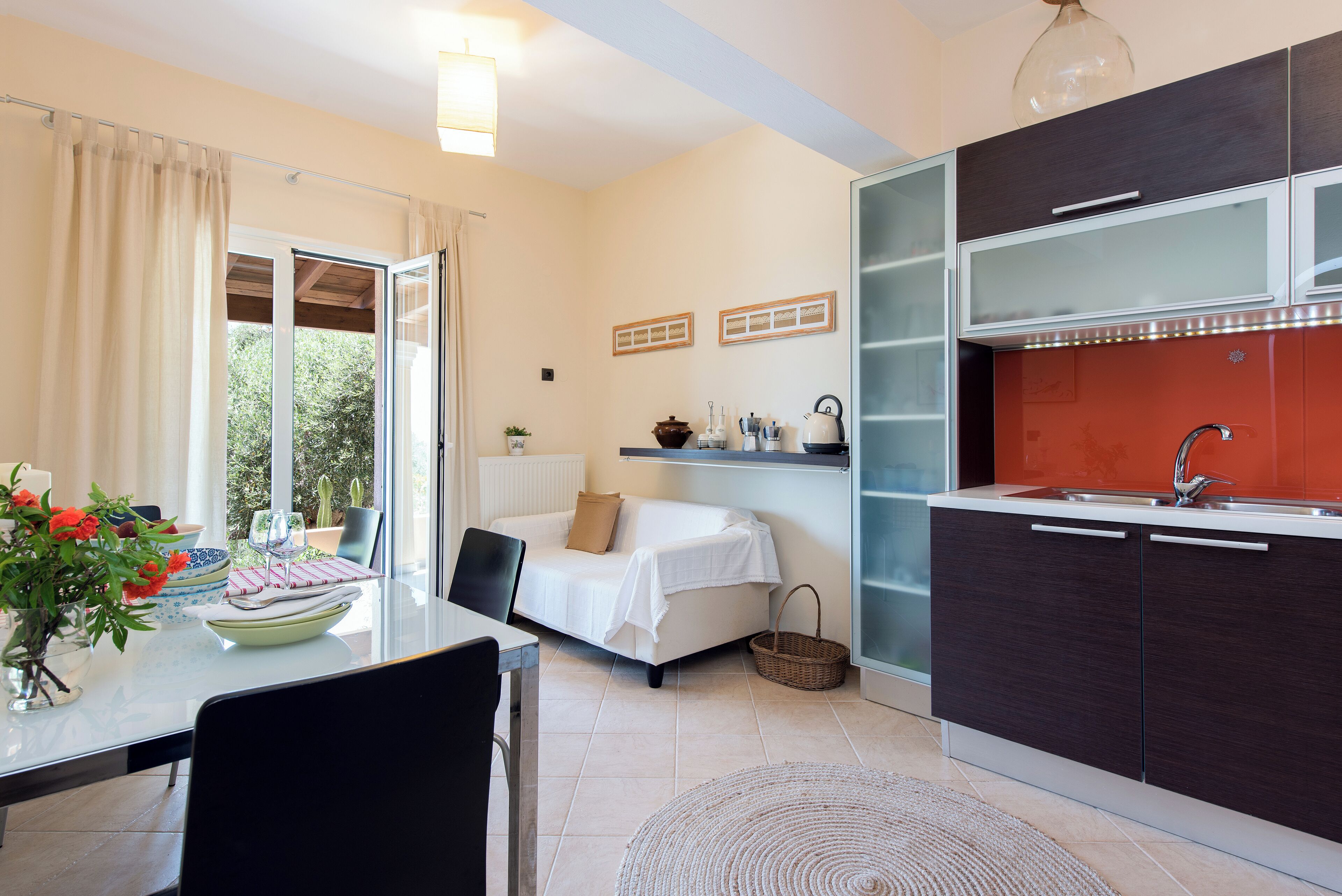 A compact living space with a dining area, kitchenette, and a sofa with a view to the outdoors.