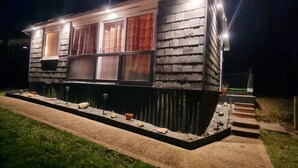 Ett litet hus i en våning med en fasad av tegel, en veranda framför och en gångstig som leder till entrén.