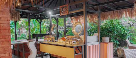 A restaurant with a thatched roof, wooden furniture, and a counter labeled "Egg Counter".