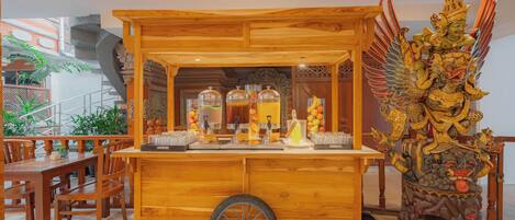 A wooden food cart with a large wheel, surrounded by traditional decor and a staircase.