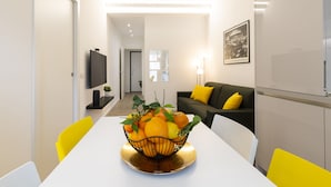 Ein modernes Wohnzimmer mit Esstisch, Sofa und Fernseher.
