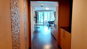 A narrow hallway with a brick wall on one side and wooden cabinets on the other. - 6D - 3 Bedroom Downtown Apartment With Shared Pool (Bangkok)