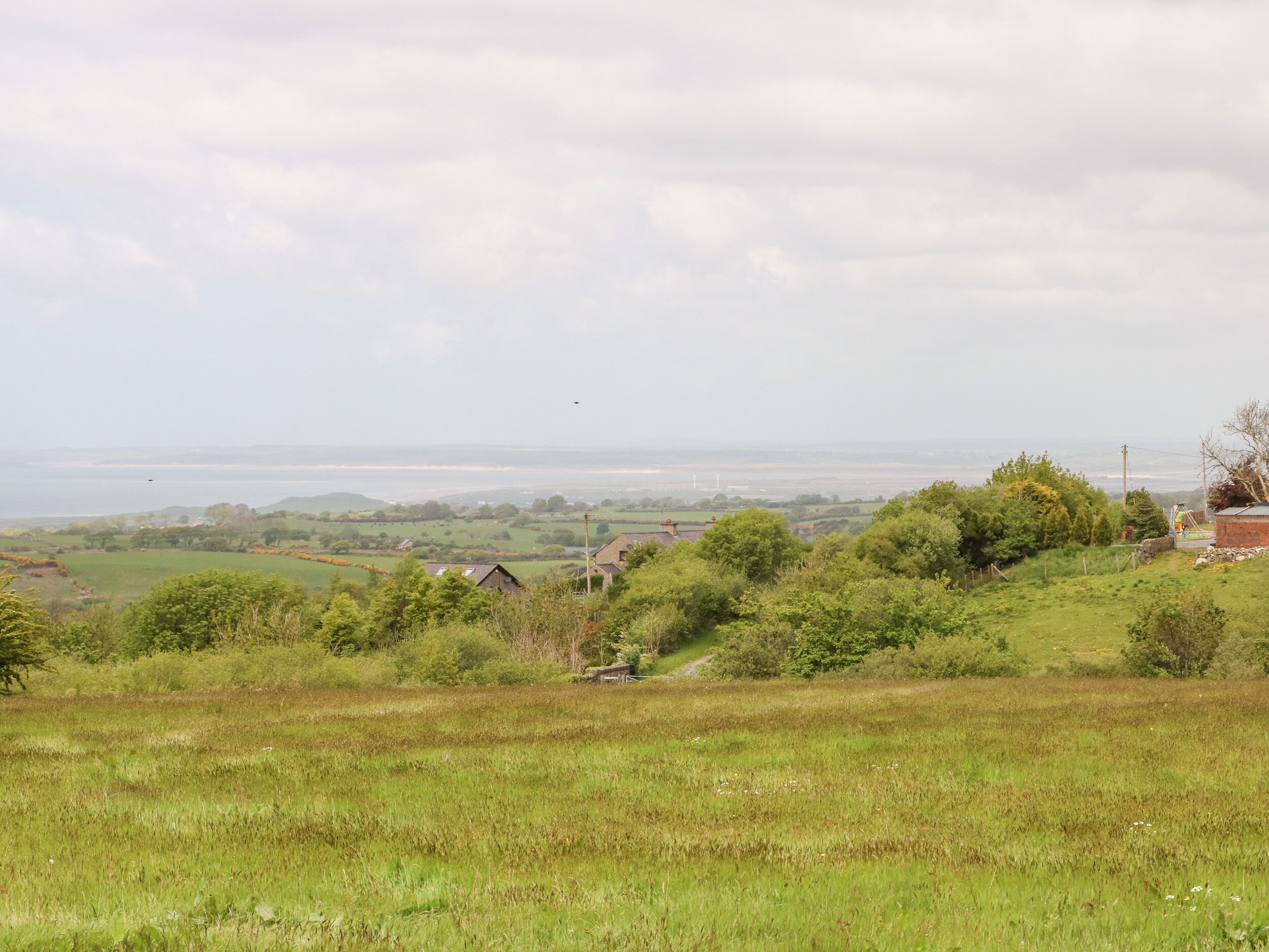 Un paisaje rural con campos, árboles y una vista distante del mar.