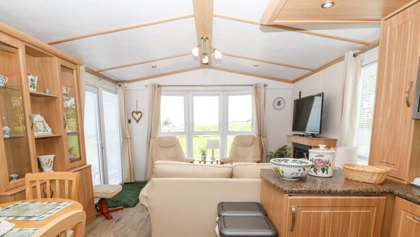 A compact RV interior with a kitchenette, a sofa, a dining table, and a trash bin. - Gwel Y Môr (Caernarfon)