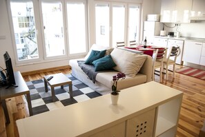 Ein modernes Wohnzimmer mit Sofa, Couchtisch und einem Essbereich mit Stühlen und Tisch.