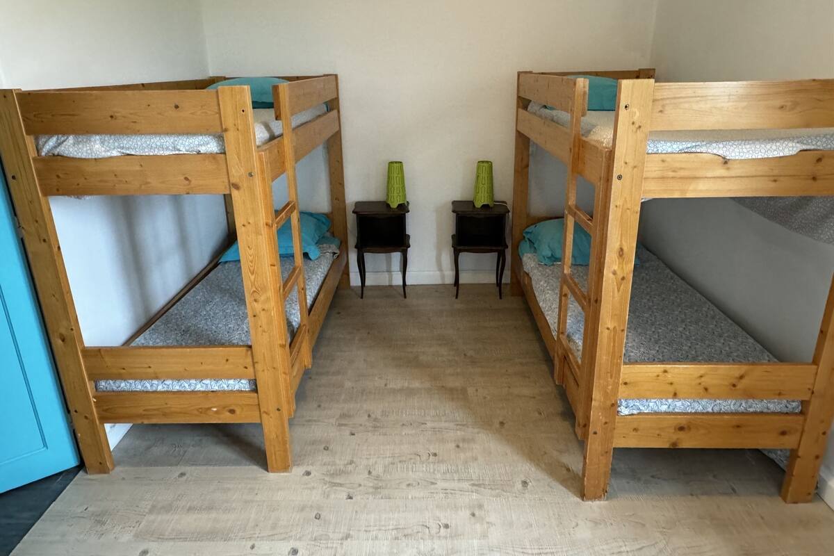 Une chambre avec deux lits superposés, une petite table et une chaise.