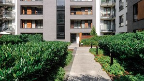 A multi-story residential building with balconies, a central entrance, and a well-maintained garden area. - Lumina apartment with balcony Warsaw (Warsaw)