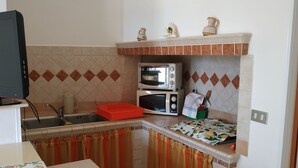 Una cocina compacta equipada con microondas, tostadora y un lavamanos pequeño.