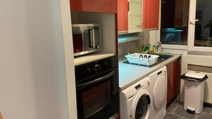 A compact kitchen with a microwave, oven, and washing machine. - Appartement T4 Rouen (Rouen)