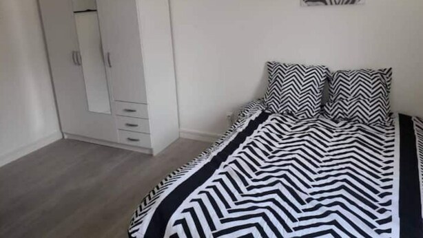 A bedroom with a bed, a wardrobe, and a zebra-patterned artwork on the wall. - Appartement T4 Rouen (Rouen)