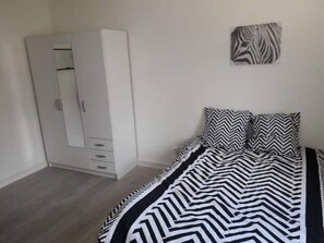 A bedroom with a bed, a wardrobe, and a zebra-patterned artwork on the wall.