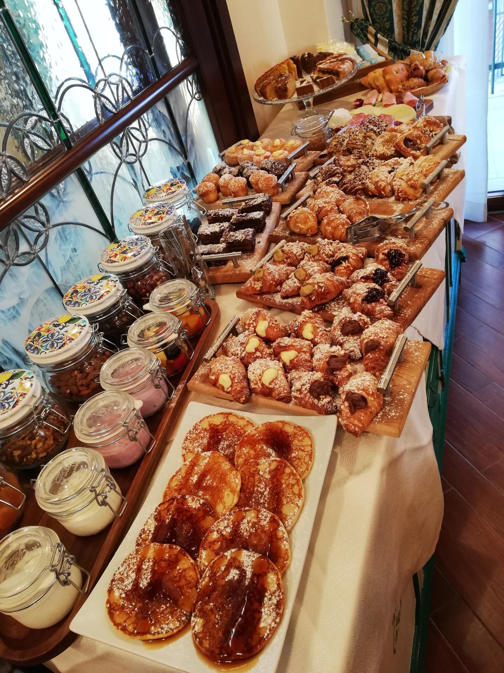 A buffet with various pastries, desserts, and condiments.