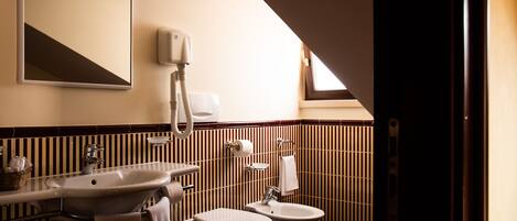Ein Badezimmer mit Waschbecken, zwei Toiletten, einem Bidet, einem Handtuchhalter und einem Spiegel.