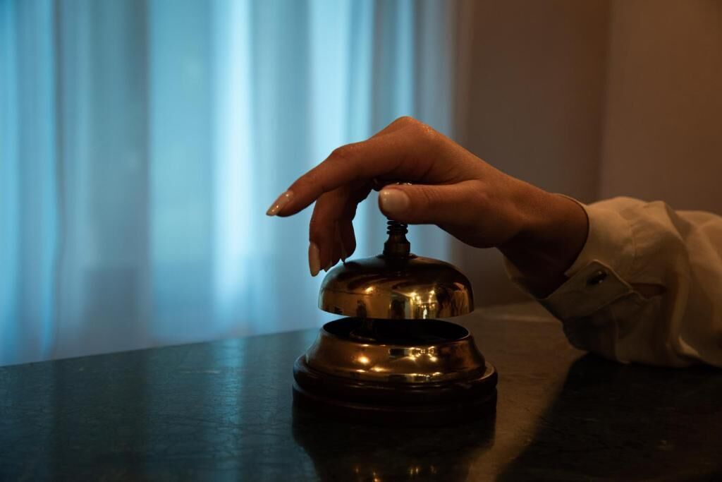 Eine Hand drückt die Klingel eines Hotelzimmers.