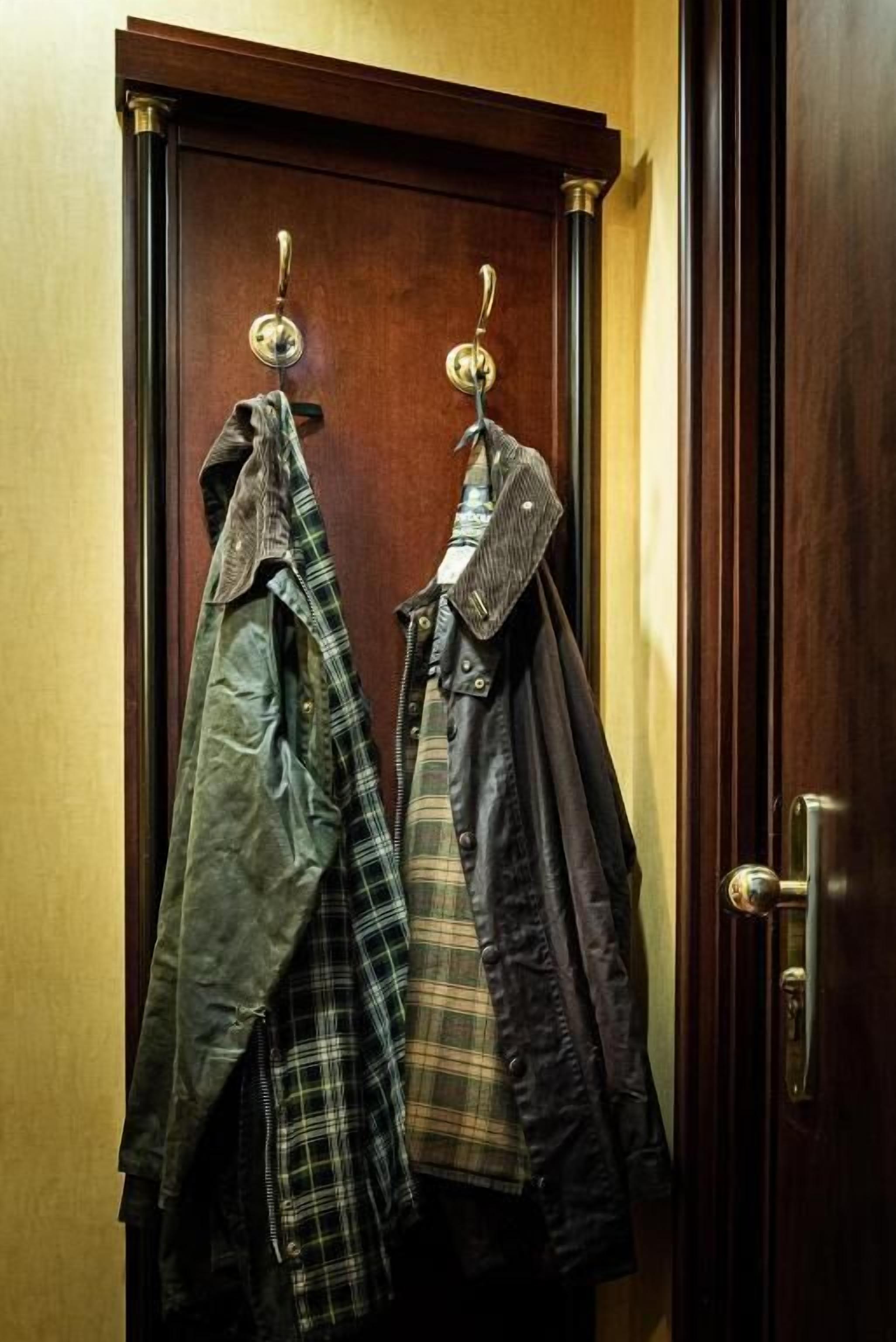 Una porta de fusta amb dues gabardines penjades en ganyots metàl·lics.